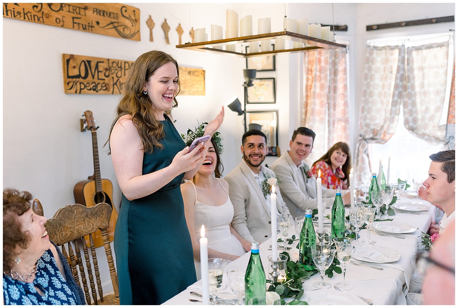 newlywed couple and friends gather around the dinner table, laughing and enjoying a toast at their own intimate home wedding dinner